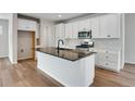 Modern kitchen featuring a central island with stone countertops, stainless steel appliances, and white cabinets at 17831 Parkside N Dr, Commerce City, CO 80022