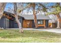 Single-story home with painted brick, wood accents, modern front door, mature trees, and well-manicured lawn at 417 S Pontiac Way, Denver, CO 80210