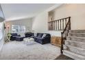Bright living room with vaulted ceilings, neutral carpet, stairs, and cozy seating area with a piano at 6212 S Ash W Cir, Centennial, CO 80121