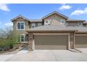 Charming townhouse featuring a stone-clad garage, neutral siding, and well-lit exterior at 22062 E Irish Dr, Aurora, CO 80016