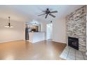 Open living space with wood floors, stone fireplace and ceiling fan open to kitchen at 5537 Lewis Ct # 4, Arvada, CO 80002