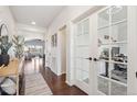 Bright hallway with hardwood floors leading to a home office with glass doors and a cozy living area at 5077 W 108Th Cir, Westminster, CO 80031