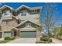 Townhouse exterior with green siding, stone accents, and a two-car garage, set in a beautifully landscaped community at 4795 E 98Th Pl, Thornton, CO 80229