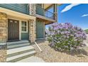 Inviting townhouse entrance with stone accents, a covered balcony, and vibrant landscaping, creating a welcoming curb appeal at 4795 E 98Th Pl, Thornton, CO 80229