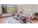 Bright living room featuring a cozy couch, chairs, and large windows with a scenic wooded view at 31402 N Bermuda Dunes Dr, Evergreen, CO 80439