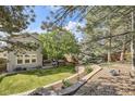 A well-maintained backyard with a mature tree, patio seating, and a tiered stone wall at 10908 Oakshire Ave, Highlands Ranch, CO 80126