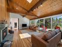 Open living space with hardwood floors, a stone fireplace, and large sliding doors to the deck at 31756 Buffalo Park Rd, Evergreen, CO 80439