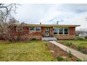 Quaint brick home with front yard and walkway leading to the front door at 345 Central Ave, Brighton, CO 80601