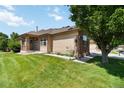 Well-manicured lawn and exterior view of this tan single-story home with brick accents at 16141 W 64Th Way, Arvada, CO 80007