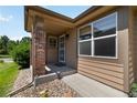 Covered front porch with brick columns, security door, and fresh landscaping at 16141 W 64Th Way, Arvada, CO 80007