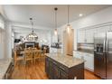 Open kitchen with granite counters, stainless appliances, island, and a view of the dining and living areas with fireplace at 19099 E Creekside Dr, Parker, CO 80134