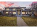 Stately brick and stucco home with a covered entrance and well-maintained landscaping at dusk at 6790 W Crestline Ave, Littleton, CO 80123