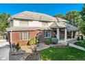 Elegant brick home featuring a manicured lawn, stone pathway, and covered porch at 6790 W Crestline Ave, Littleton, CO 80123