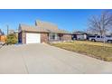 Brick ranch house with attached garage and paved driveway at 5621 Demott Ave, Commerce City, CO 80022