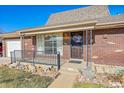 Brick home's front entrance with a metal railing and walkway at 5621 Demott Ave, Commerce City, CO 80022