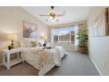 This bedroom boasts soft natural light from a large window with a ceiling fan and stylish décor at 8406 Pebble Creek Way # 202, Highlands Ranch, CO 80126