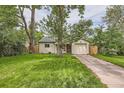 Inviting home showcasing a green lawn, mature trees, and attached garage for convenient parking at 2565 S Gaylord St, Denver, CO 80210