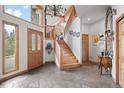 Grand foyer with flagstone flooring, wood staircase, and beautiful chandelier creates an inviting entrance at 32209 Blue Springs Dr, Evergreen, CO 80439