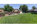Expansive backyard featuring a well-kept lawn, patio seating area, and storage shed at 12143 Dahlia Dr, Thornton, CO 80241