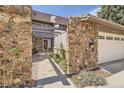 Close-up of the entrance features stone pillars, a pergola, manicured landscaping and inviting walkway at 6922 W Walden Pl, Littleton, CO 80128