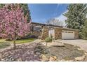 Landscaped front yard featuring a beautiful tree, rock features and vibrant flowers enhancing the curb appeal at 6922 W Walden Pl, Littleton, CO 80128