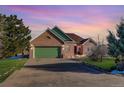 Inviting brick home featuring a green garage door, lush landscaping, and a spacious driveway at 4270 Defoe St, Strasburg, CO 80136