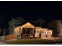 Night view of a charming two-story home with a covered porch and three-car garage at 12405 E 101St Dr, Commerce City, CO 80022