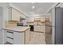 Functional kitchen features a breakfast bar, stainless steel refrigerator, and ample cabinet space at 235 S Monaco Pkwy, Denver, CO 80224