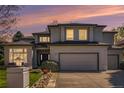 Charming two-story stucco home featuring a manicured lawn and an attached two-car garage during sunset at 3002 S Oak Way, Lakewood, CO 80227