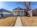 Inviting yellow home showcasing a cozy covered porch and manicured lawn for idyllic curb appeal at 219 Terry St, Longmont, CO 80501