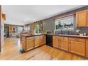 Bright kitchen featuring wood floors, stainless sink, wood cabinets and a large window at 1086 Mockingbird St, Brighton, CO 80601