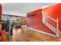 Bright living room featuring hardwood floors, wooden accent walls, and stairs with white banister at 1086 Mockingbird St, Brighton, CO 80601