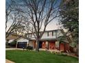 Charming home with a brick facade, attached garage, and lush green lawn and mature trees at 8736 E Easter Ave, Centennial, CO 80112