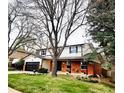 Charming home with a brick facade, attached garage, and lush green lawn and mature trees at 8736 E Easter Ave, Centennial, CO 80112