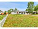 Wide angle of a home with a large lawn, a white picket fence, and a two car garage at 4680 Independence St, Wheat Ridge, CO 80033