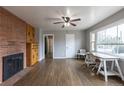 Bright living room with a brick accent wall, hardwood floors, a ceiling fan, and a large picture window at 1345 Laredo St, Aurora, CO 80011