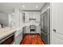 Well-equipped kitchen with white cabinets, stainless steel appliances, a farmhouse sink, and a marble backsplash at 6135 S Paris St, Englewood, CO 80111