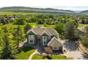 Aerial view of a beautiful home showcasing landscaped grounds, mature trees, and stunning mountain views at 50 Deerwood Dr, Littleton, CO 80127