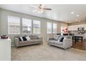 Open-concept living room with neutral tones, large windows, and modern ceiling fan at 6491 N Danube St, Denver, CO 80249
