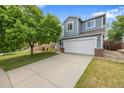 Two-story home with an attached garage, a large driveway, and a mature tree in the front yard at 18121 E Adriatic, Aurora, CO 80013