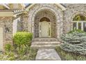Inviting front entrance with an arched brick porch, detailed trim, and manicured bushes at 85 Silver Fox Dr, Greenwood Village, CO 80121