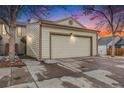 Exterior view of a two-car garage with a concrete driveway at dusk at 14204 E Baltic Cir, Aurora, CO 80014