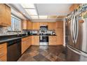 Cozy kitchen with wood cabinets, black countertops, stainless steel appliances, and stone flooring at 14204 E Baltic Cir, Aurora, CO 80014