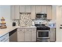 Modern kitchen featuring stainless steel appliances and gray cabinets with a mosaic backsplash at 4810 W 8Th Ave, Denver, CO 80204