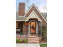 Inviting front entrance with stone steps, wrought iron railing, and a decorative door, framed by lush greenery at 1055 S Clayton Way, Denver, CO 80209