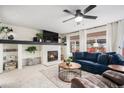 Cozy living room with fireplace, ceiling fan, large windows, and a comfortable blue sofa, perfect for relaxation and entertaining at 15776 E 107Th Way, Commerce City, CO 80022