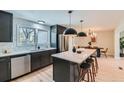 Kitchen area with a white marble island with seating, black cabinets, modern lighting, and stainless steel appliances at 4682 Chatham St, Boulder, CO 80301