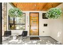 Inviting front porch featuring stylish seating, hanging flower baskets, and a modern front door at 3957 Utica St, Denver, CO 80212