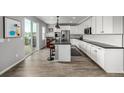 Modern, open kitchen with white cabinets, a large island, stainless steel appliances, and wood flooring at 9406 Bross St, Arvada, CO 80007