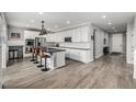 Modern, open kitchen with white cabinets, a large island, stainless steel appliances, and wood flooring at 9406 Bross St, Arvada, CO 80007